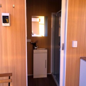 A compact bathroom with a mirror, sink, and cabinet.