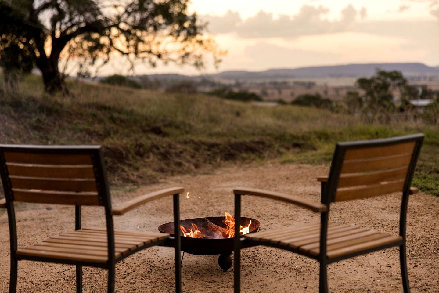 Two chairs facing a fire pit with a view of a landscape.