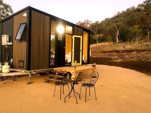 A modern cabin with a dining area featuring a table and chairs, a small kitchen area, and a large window.