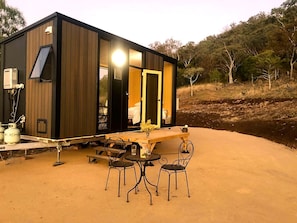 Una cabana moderna amb zona de dinar que inclou taula i cadires, un espai cuina petit i una finestra gran.