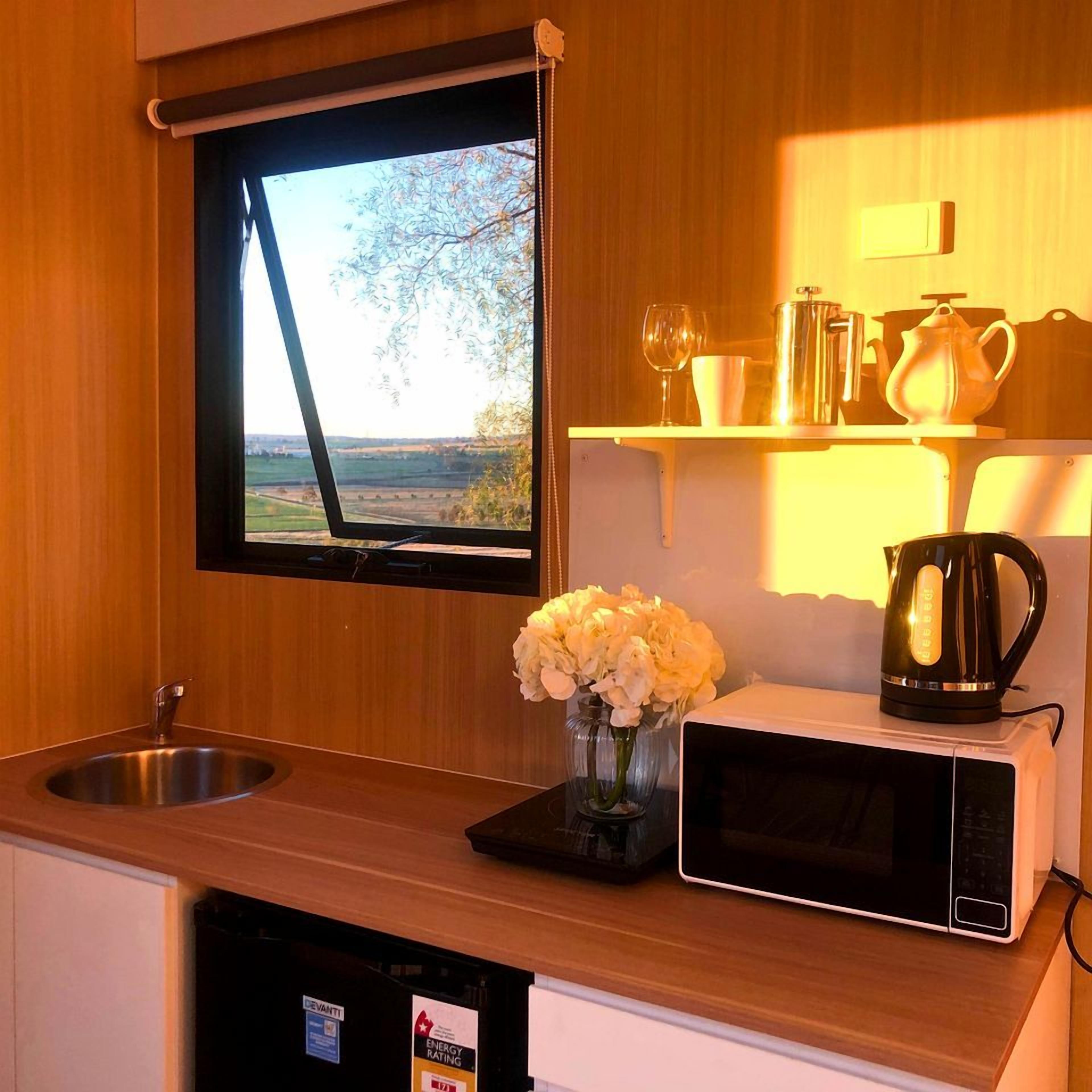 A kitchen with a window, a sink, a microwave, and a vase with flowers.