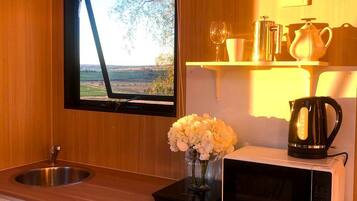 A kitchen with a window, a sink, a microwave, and a vase with flowers.