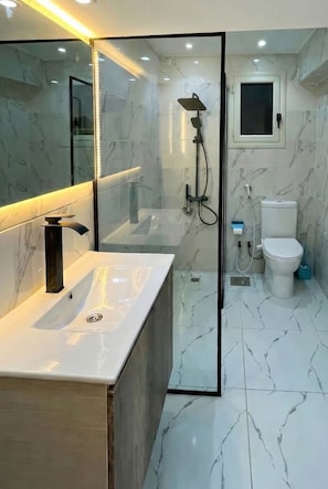 A modern bathroom with a glass shower enclosure, a white sink, and a toilet. - 2BRs Hasan Alma'moon Fabulous Apartment (Cairo Governorate)