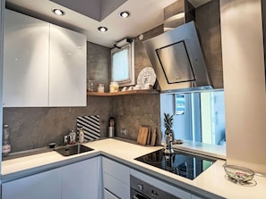 Eine moderne Küche mit eingebautem Backofen, einer Edelstahl-Dunstabzugshaube und einem Fenster über der Spüle.