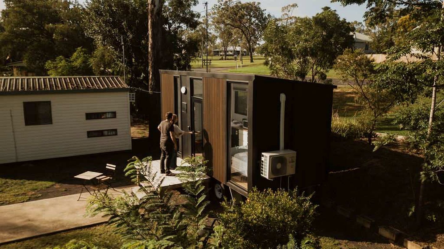 A compact mobile home with a small porch and a person standing at the door.