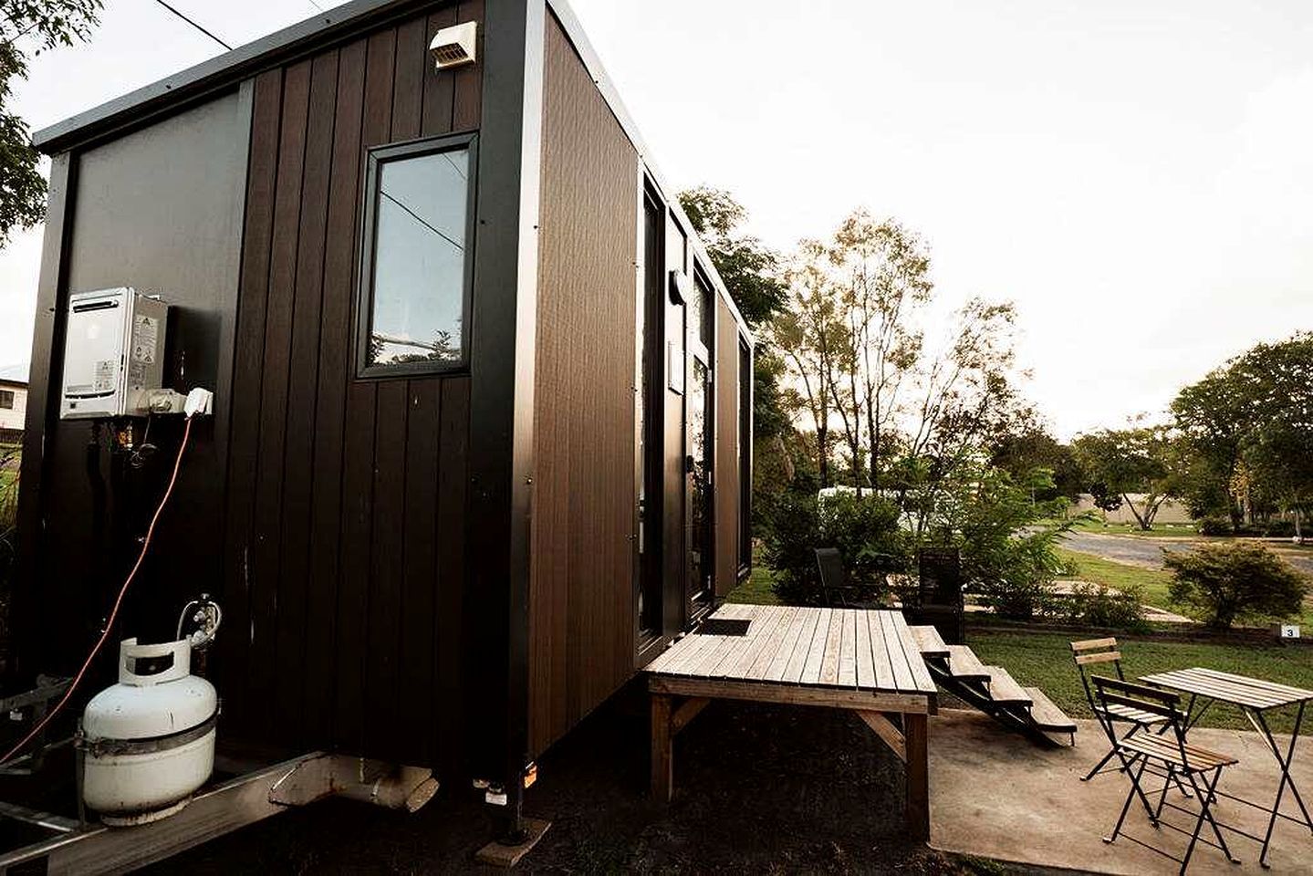 A compact wooden cabin with a small deck and outdoor seating.
