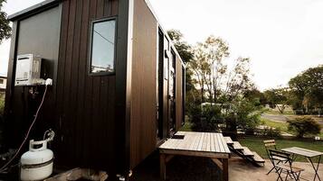 A compact wooden cabin with a small deck and outdoor seating.