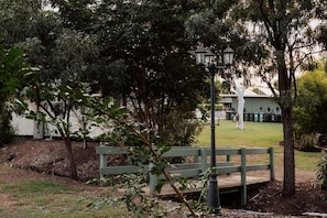 A park area with a wooden bench, a lamp post, and a building in the background.