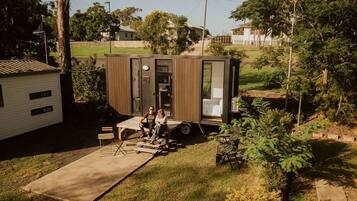 Une petite maison mobile d’un seul étage, dotée d’un porche, d’une porte coulissante et d’une petite terrasse.