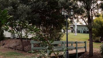A park area with a wooden bench, a lamp post, and a building in the background.