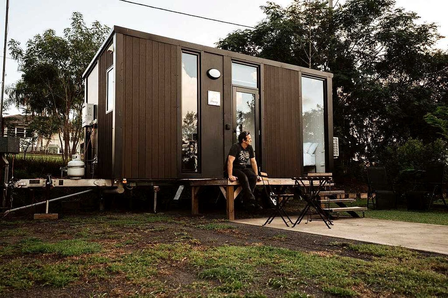Una casa móvil moderna y compacta con techo plano, ventanas amplias y un pequeño porche.