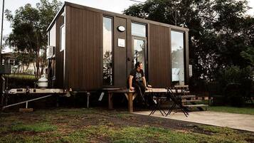 Una casa móvil moderna y compacta con techo plano, ventanas amplias y un pequeño porche.
