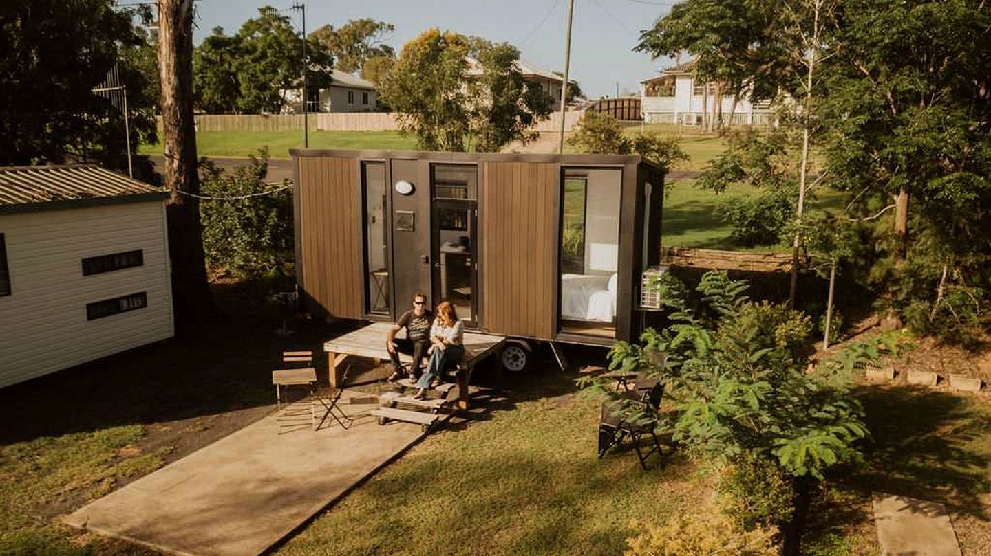 A small, single-story mobile home with a porch, a sliding door, and a small deck.