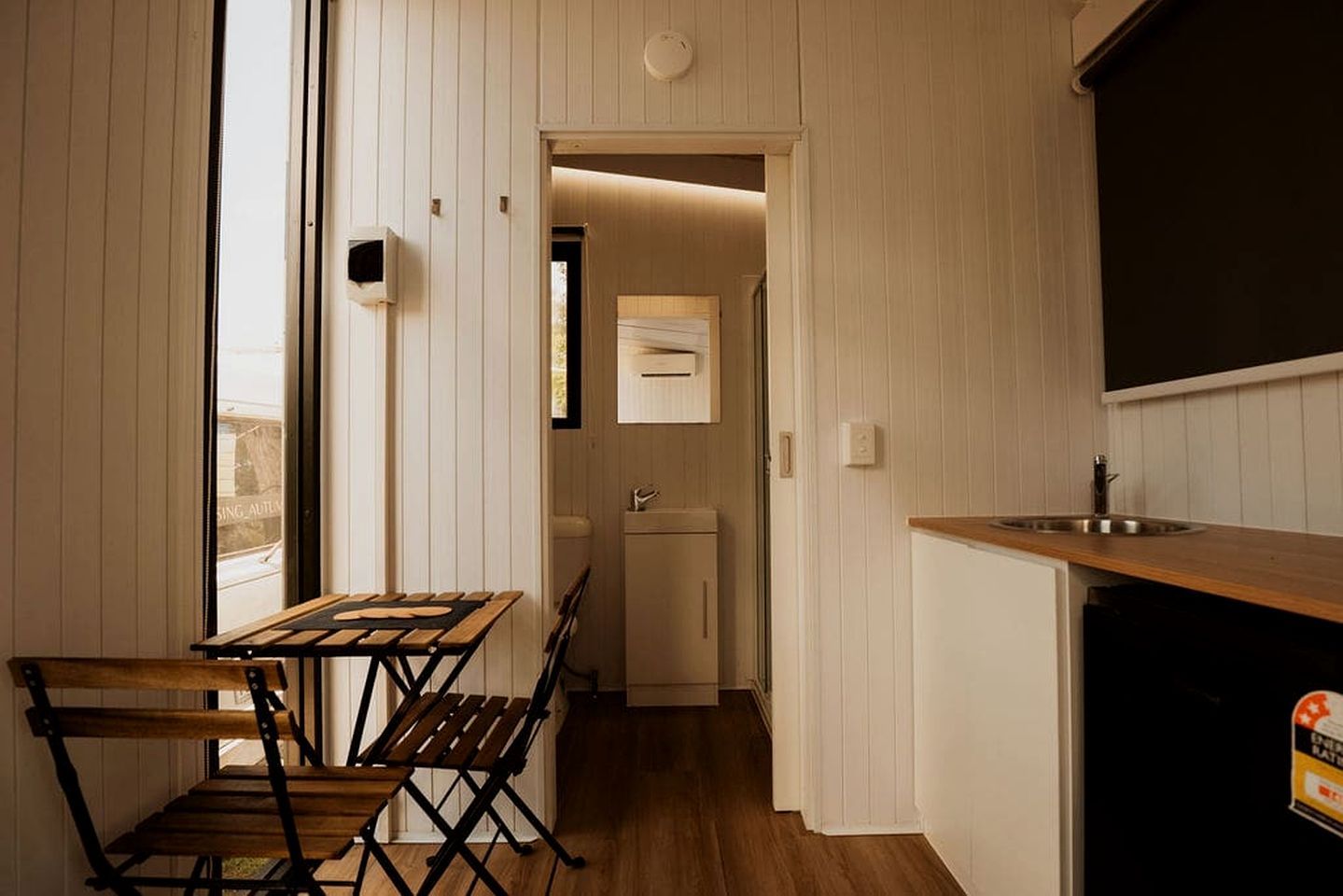 A compact kitchen with a dining area, a small refrigerator, and a sink.