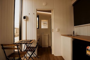 A compact kitchen with a dining area, a small refrigerator, and a sink.