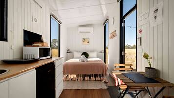 A compact bedroom with a bed, bedside table, and a view of the outdoors.
