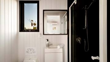 A bathroom with a toilet, sink, mirror, and shower.