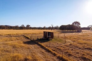 A small wooden structure in an open field with a clear sky.