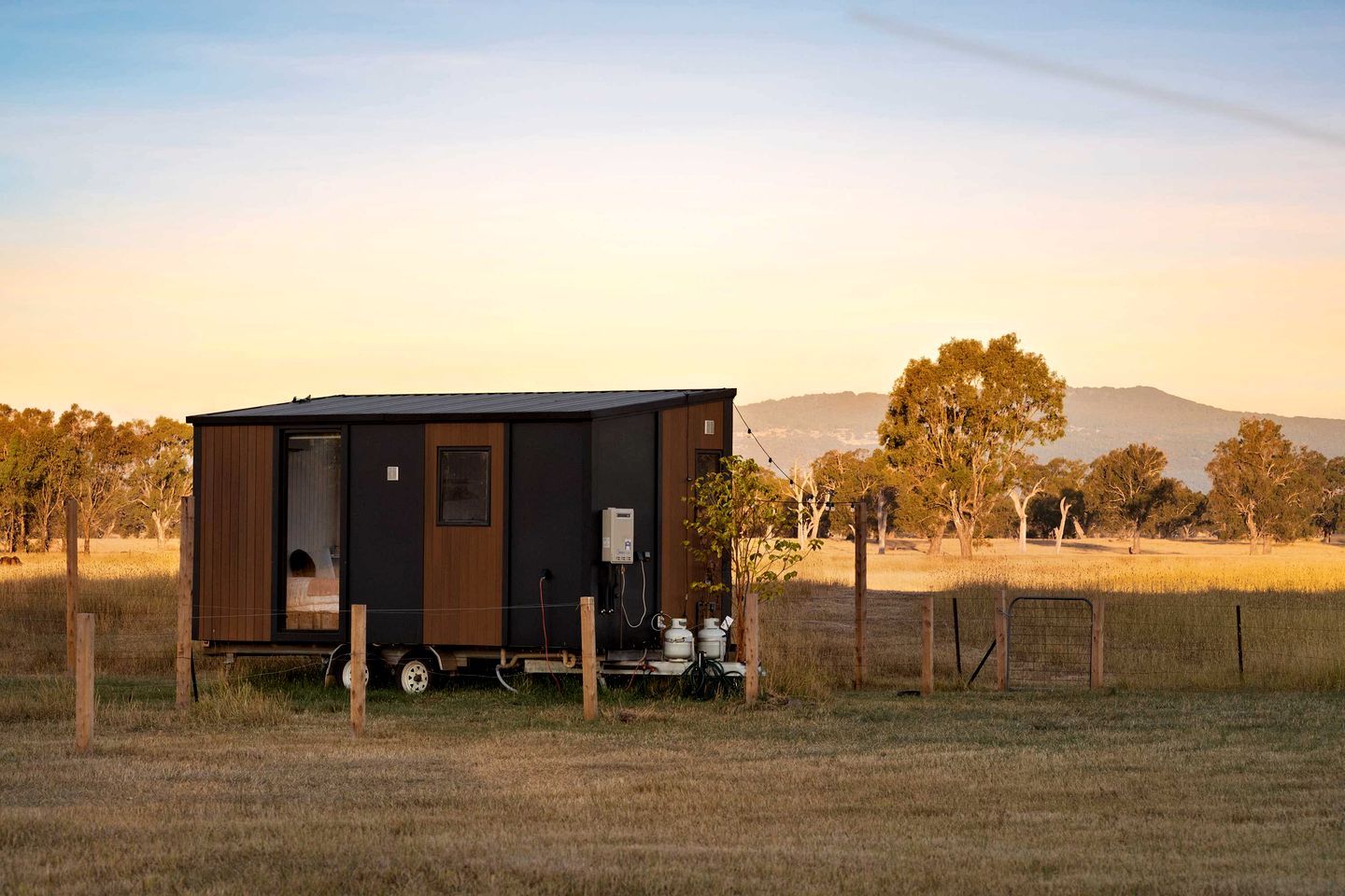 A single-story mobile home with a front door, a small window, and a visible water heater outside.