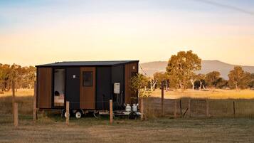 A single-story mobile home with a front door, a small window, and a visible water heater outside.
