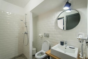 A bathroom with white tiled walls, a shower, a toilet, and a sink with a mirror above it. - THE PINES BOUTIQUE VILLA BRASOV (Brașov)