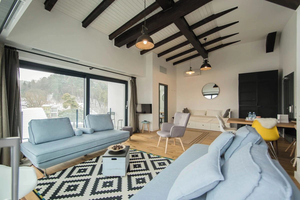 A modern living room with a sofa, a coffee table, and a dining area with a chair and table.