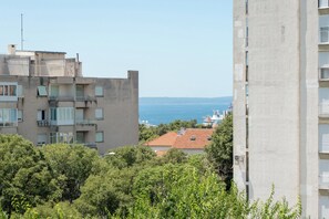 A multi-story building with balconies, a view of the sea, and surrounding greenery. - Modern 90 m2 apartment with balcony and the sea view (Split)