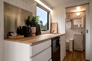 A compact kitchen with a wooden countertop, a sink, a dishwasher, and a window providing natural light.
