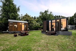 Two modern cabins with large windows, wooden decks, and outdoor seating areas.