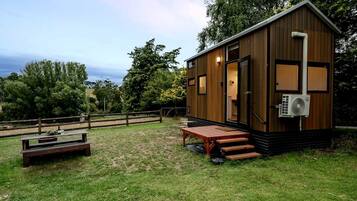 A small wooden cabin with a porch, a picnic table, and a view of the surrounding landscape.