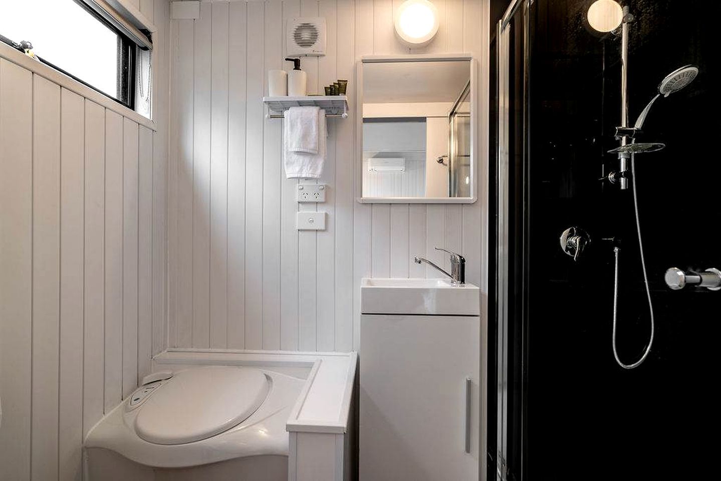 A bathroom with a white sink, a mirror, a towel rack, and a shower with a handheld showerhead.