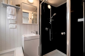 A bathroom with a white sink, a mirror, and a shower enclosure.