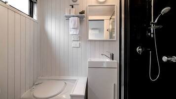 A bathroom with a white sink, a mirror, a towel rack, and a shower with a handheld showerhead.