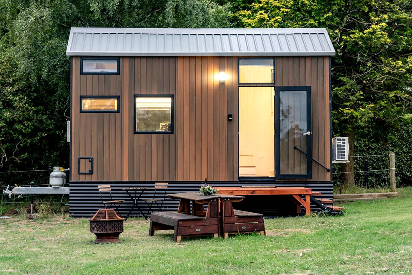 A small wooden cabin with a metal roof, a sliding door, and a window.