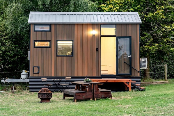 A small wooden cabin with a metal roof, a sliding door, and a window.