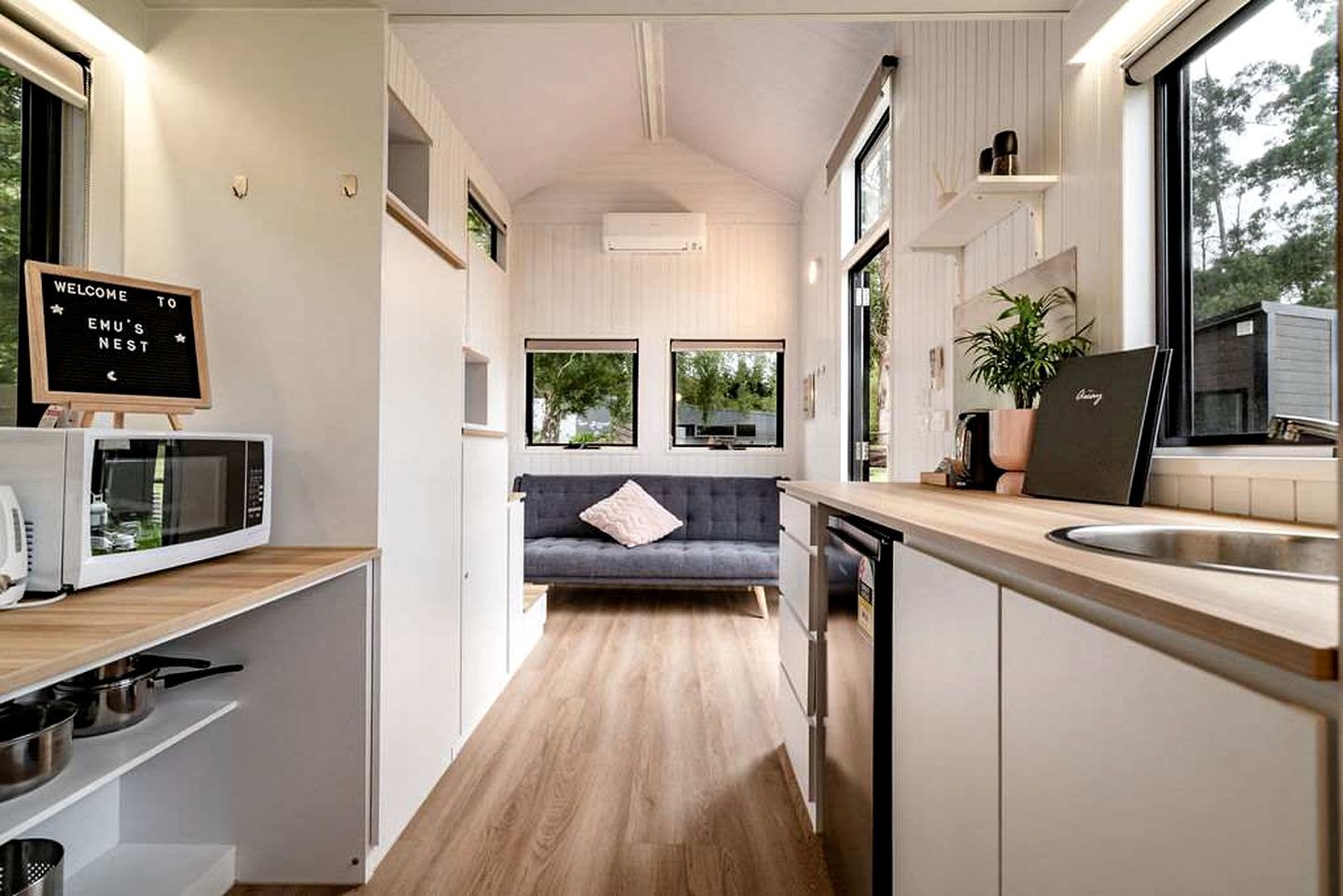 Eine kleine Küche mit Mikrowelle, Spüle und einem Sofa im Hintergrund.