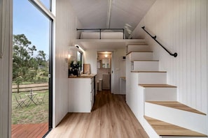 A modern interior with a kitchen area, wooden flooring, and a staircase.