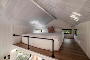 A bedroom with a bunk bed, a window, and a balcony.