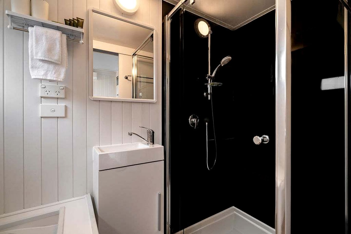 A bathroom with a white sink, a mirror, and a shower enclosure.