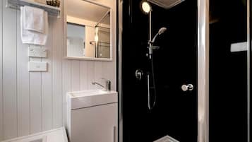 A bathroom with a white sink, a mirror, and a shower enclosure.