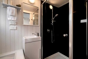 Une salle de bain avec un lavabo blanc, un miroir et un espace douche.