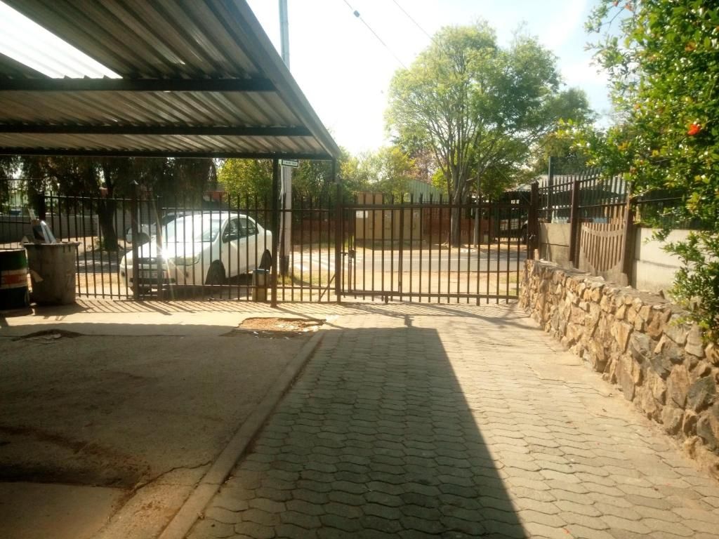 A paved driveway leading to a gated entrance with a parked car.