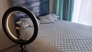 A bedroom with a bed, a headboard, and a ring light.