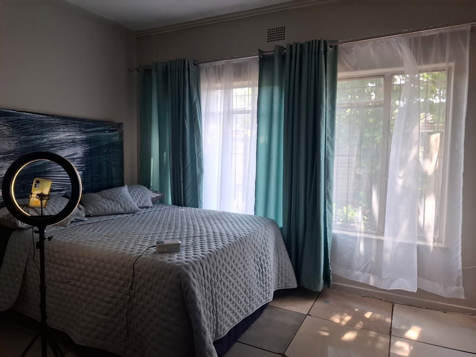 A bedroom with a bed, a ring light, and curtains.