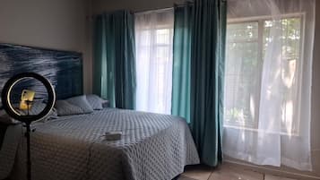 A bedroom with a bed, a ring light, and curtains.