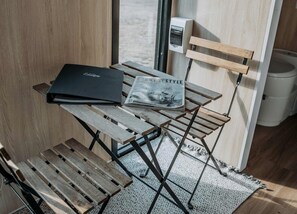 A wooden table with a magazine and a black folder. - Cozy Secluded Tiny House in Warialda, New South Wales (Warialda)