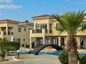 Un hotel con piscina, un puente y una palmera.