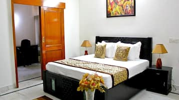 A hotel room with a bed, bedside lamps, a painting on the wall, and a vase with flowers on the table.