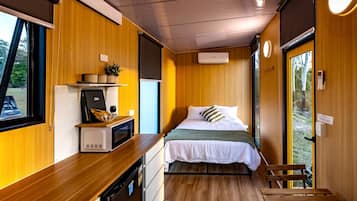A compact room with a bed, a microwave, a small table, and a window.