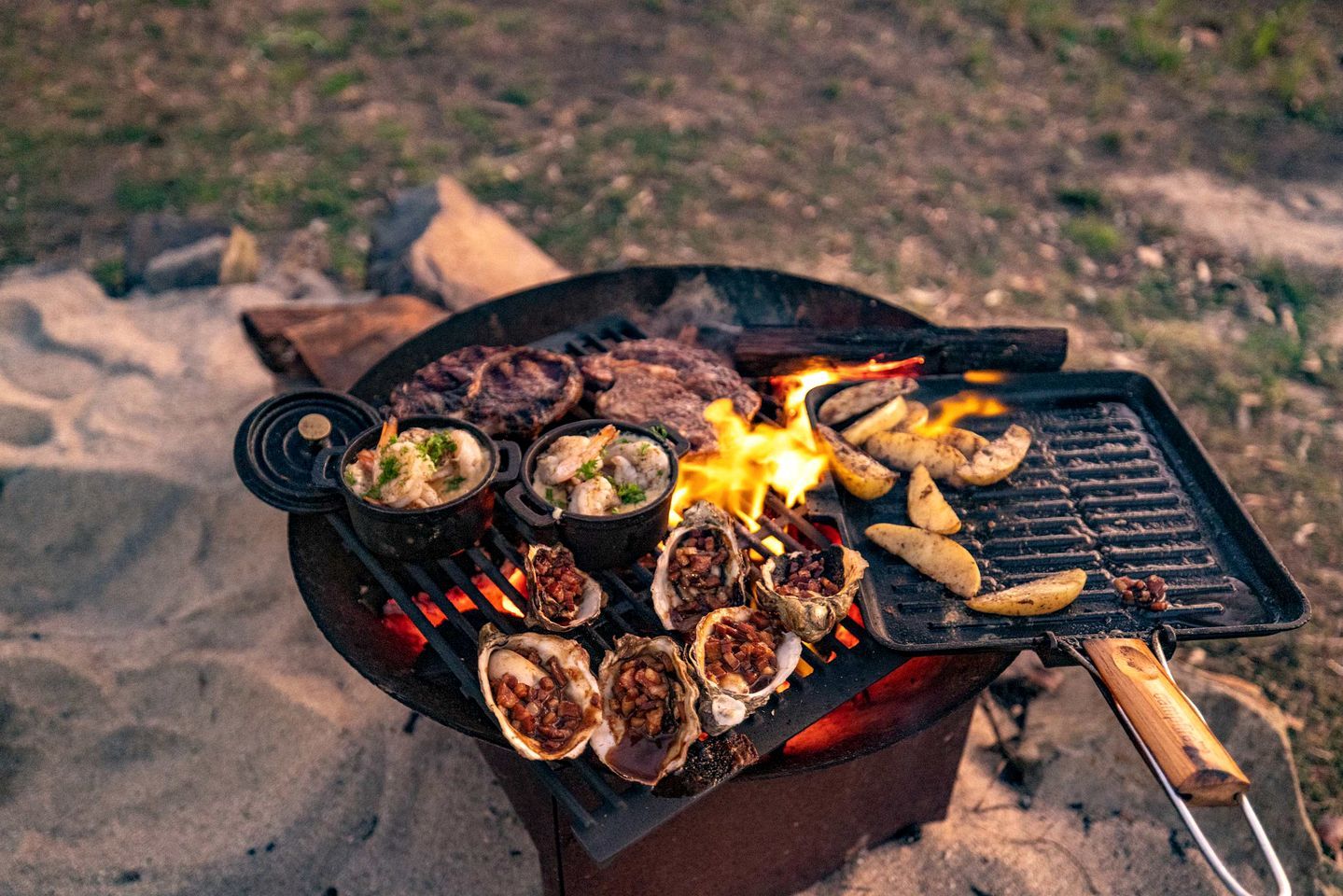 A grill with seafood, meat, and vegetables being cooked outdoors.
